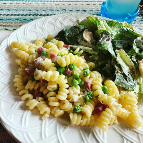 plate of pasta with ham and peas